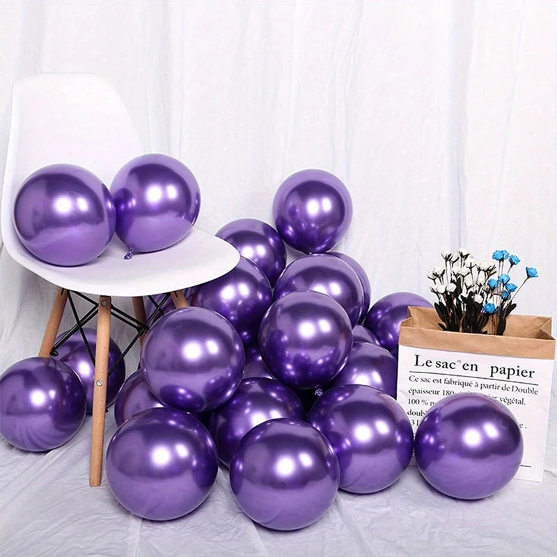 A cluster of Candletown.net shiny purple latex balloons is scattered on the floor and white chair, next to a brown paper bag filled with small white and blue flowers, creating festive party decorations and a vibrant atmosphere.